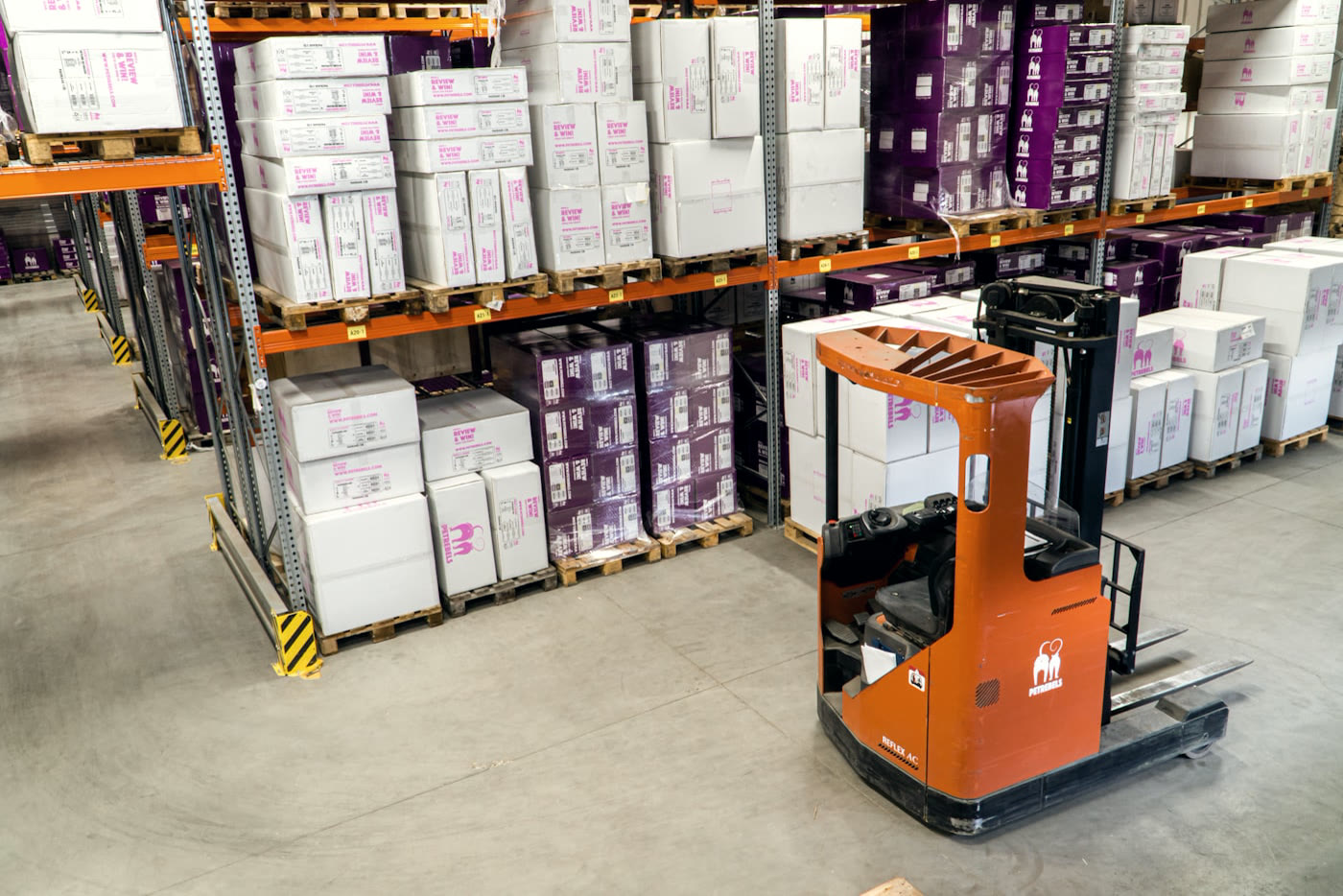 A warehouse aisle with a reach truck between racks